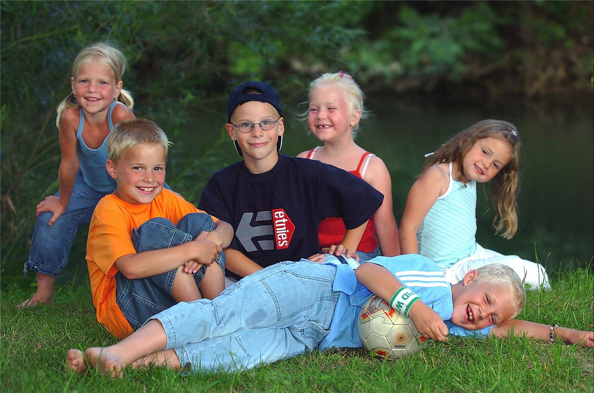 eine Gruppe Kinder sitzen und stehen im Gras