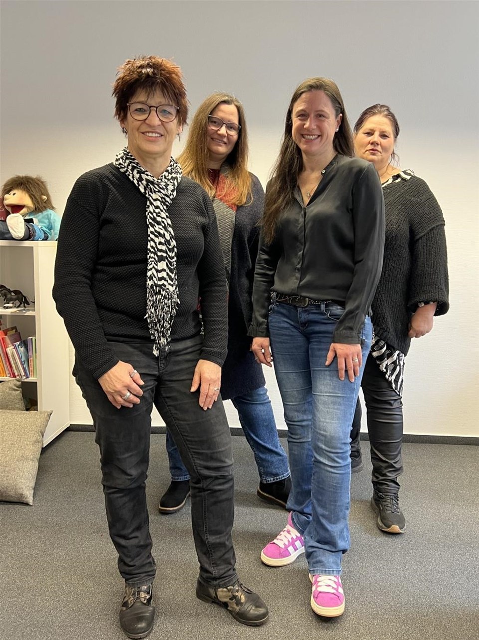 Das vierköpfige Team präsentiert sich stehend in ihren Büroräumen. 